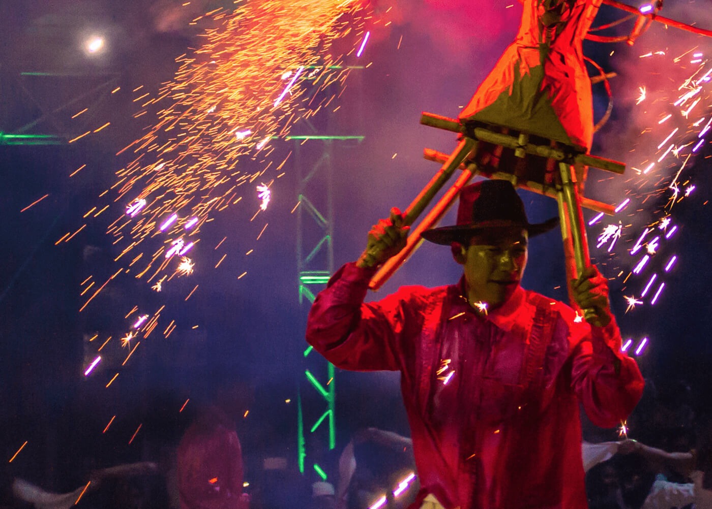 hombre sosteniendo un articulo de madera tradicional rodeado de fuegos artificiales